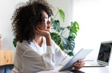 young woman working at home office using multiple devices
