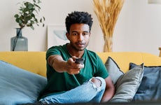 Entertained man watching a movie on TV turning up the volume